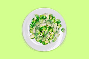Lightly fried brussels sprouts on a white plate on the solid color drop