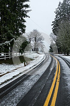 A lightly snow covered road just outside Portland, Oregon, USA, the double yellow lines leading off into the distance