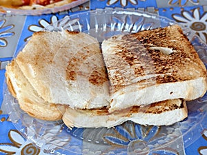 Lightly toasted white bread slices stacked on plate.