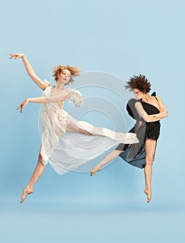 Lightness and dark. Young beautiful women in image of angle and devil against blue background. Ballet dance