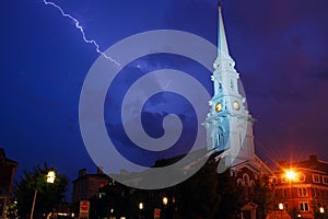 A lightning bolt flashes across the sky near a historic church