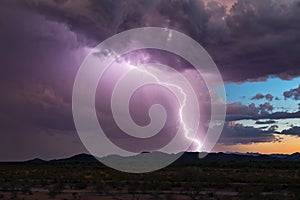 Lightning bolt from a monsoon storm against a sunset background.