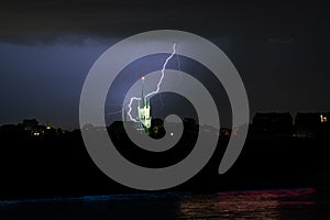 Lightning bolt strikes behind a church near a river