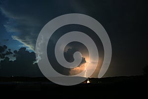 Lightning bolt strikes down to earth from the cloud of a thunderstorm at dusk