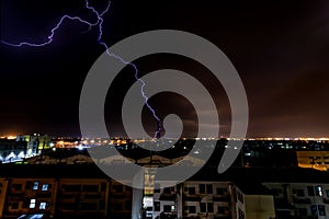 Lightning bolt strikes tower in industrial area at night