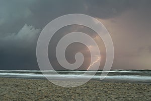 Lightning bolt strikes in the water from a thunderstorm over sea