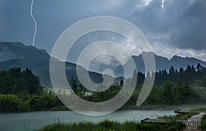 Lightning bolt striking a hill above lake.