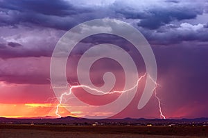 Lightning bolt at sunset with dark storm clouds