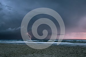 Lightning bolt from a thunderstorm over sea at sunset