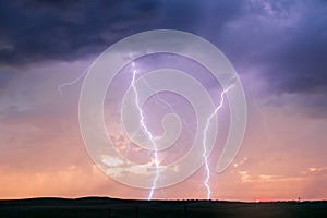 Lightning bolts strike in a thunderstorm at sunset