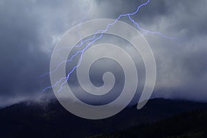 Lightning in the Dark Sky with Storm Clouds Over the Mountains