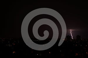 Lightning flashes over the night city. Discharge of electricity in the night sky.