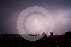 Lightning flashes over the night city. Discharge of electricity in the night sky.