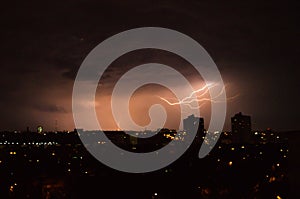 Lightning flashes over the night city. Discharge of electricity in the night sky.