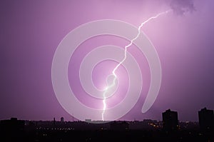 Lightning flashes over the night city. Discharge of electricity in the night sky.