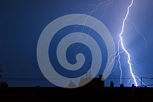 Lightning hitting building rooftops in thunderstorm