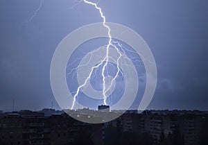 Lightning in the night sky strikes the roof of the house