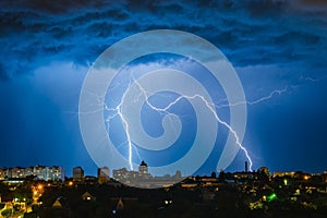 Lightning over the city in the night sky strikes the roof of the house