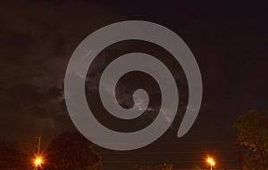 Lightning with rain cloud in night and lamp post on street