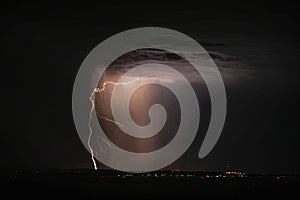 Lightning and storm clouds over the sea and the city.