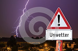 Lightning storm in the evening with city lights german warning sign