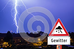 Lightning storm in the evening with city lights german warning sign