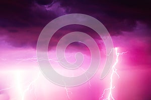 A lightning strike on the cloudy sky. Pink, lilac and purple toned image