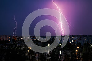 Lightning strikes down over the city at night.