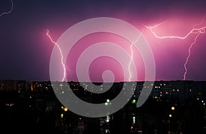 Lightning strikes down over the city at night.