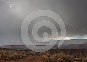 Lightning strikes in a hailstorm above Zion National park with an old cedar post corral in the foreground