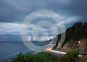 Lightning thunderbolt in sea at twilight with lighting from cars