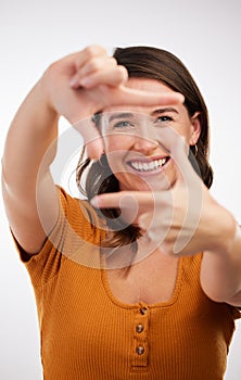 Lights, camera, action. Studio shot of a young woman making a frame with her hands against a white background.