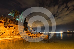 Lights of the coastal city reflecting in the sea at night