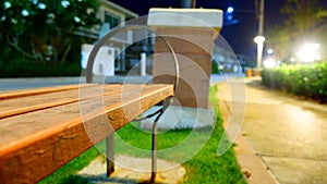 The lights that illuminate between orange benches sit on the side of the garden path at night.