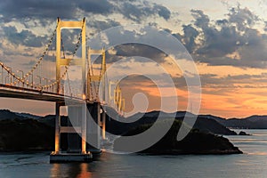 Lights from Kurushima Bridge mix with sunset glow over islands in Seto Inland Sea