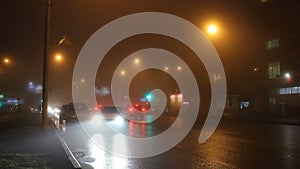 The lights of night city in fog and cars on road.