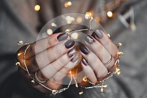 Lights in the palms. Women`s hands holding a garland. Girl in a blue sweater