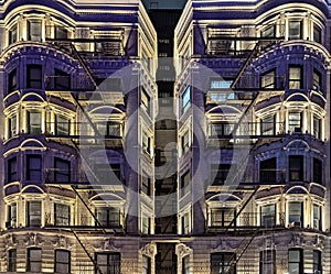 Lights shining on old apartment building in New York City at night