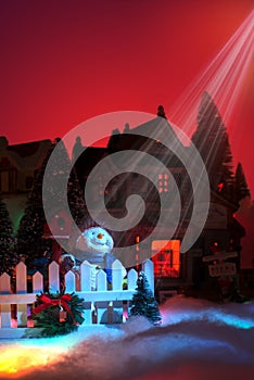 Lights from star of bethlehem shines down on happy snowman`s face. christmas miniature village