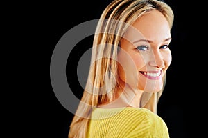 She lights up any room. Studio portrait of a beautiful young blonde woman looking over her shoulder isolated on black.