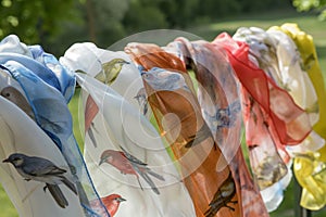 lightweight scarves with bird motifs placed on a rack outdoors