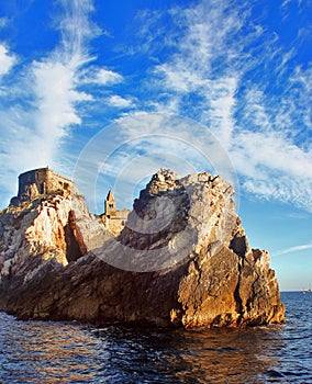 Liguria: the Saint Peter church of Portovenere on the cliff rockview and blue sky with clouds from the boat in the afternoon