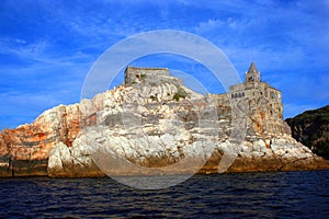 Liguria: the Saint Peter church of Portovenere on the cliff rockview and blue sky with clouds from the boat in the aftenoon