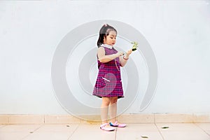 Liitle asian girl standing alone and holding a small plant in the hand