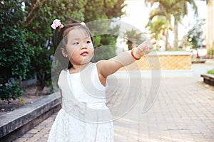Liitle asian girl standing and poiting finger to the right. Future children concept