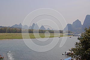 Lijiang River between Guilin and Yangshuo, China with boats cruising down the river with the misty karst mountains