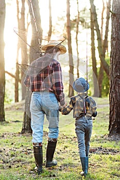 Likable confident bearded grandpa in forest going fishing together with his 10-aged grandson and talking about fishing.