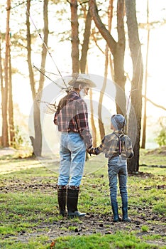 Likable confident bearded grandpa in forest going fishing together with his 10-aged grandson and talking about fishing.