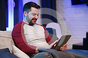 Slow motion of likable modern good-natured 30-aged man with well-groomed beard which resting on the sofa at home and photo