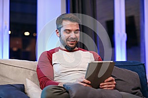 Slow motion of likable modern good-natured 30-aged man with well-groomed beard which resting on the sofa at home and photo